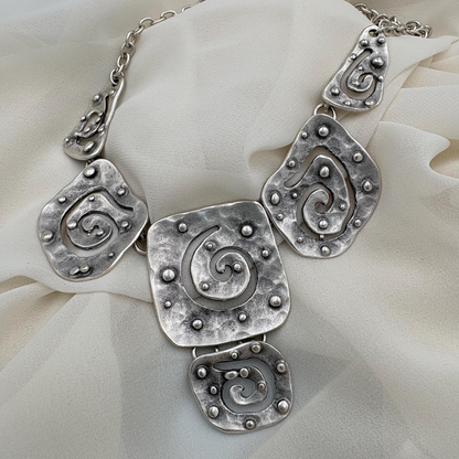 Bohemian style silver pendant necklace worn with a casual black top.