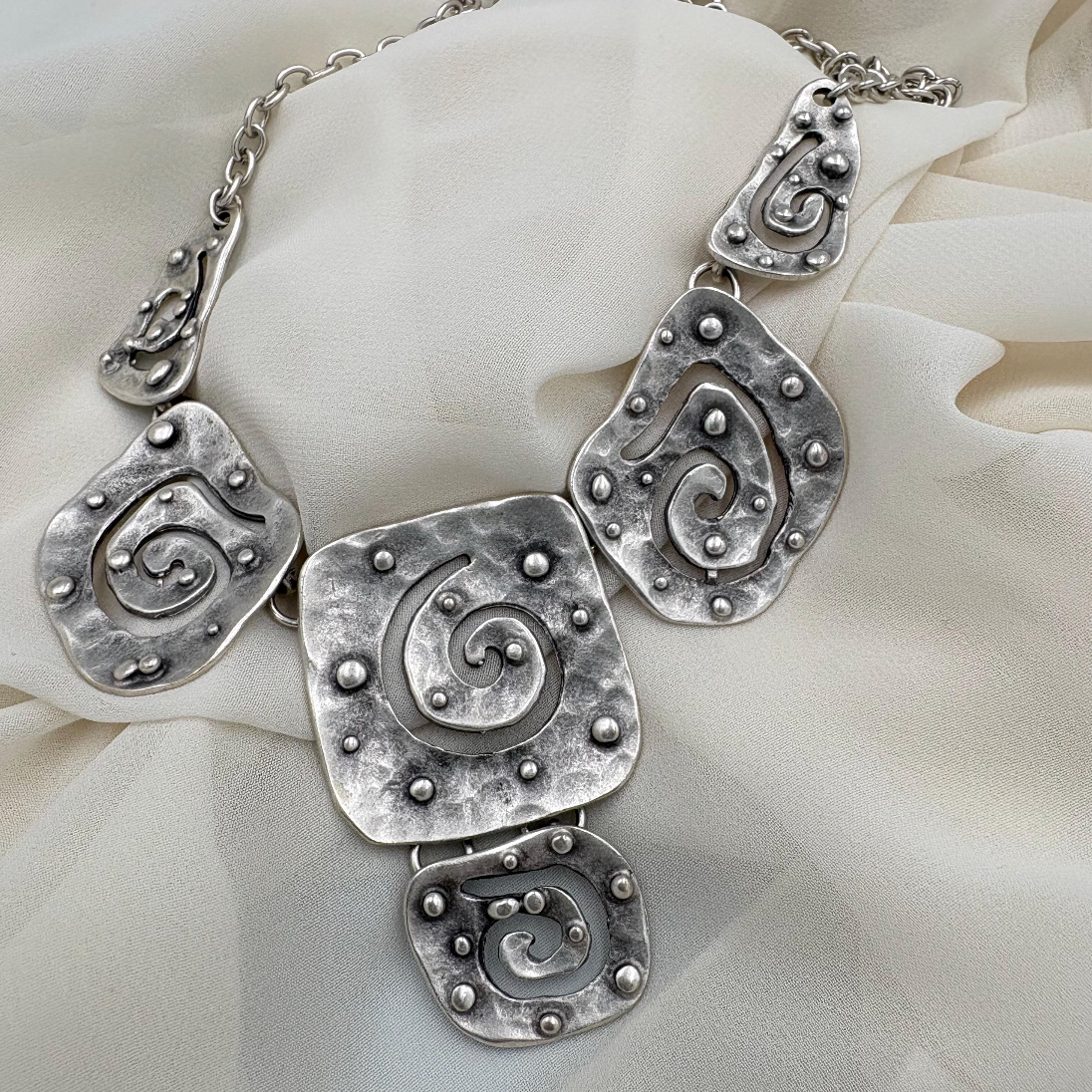 Detailed view of a vintage silver necklace with unique abstract spiral patterns.