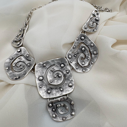 Detailed view of a vintage silver necklace with unique abstract spiral patterns.