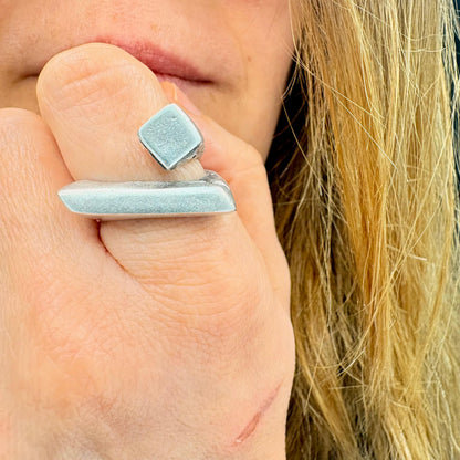 Close-up of a hand wearing two silver rings with a blurred background