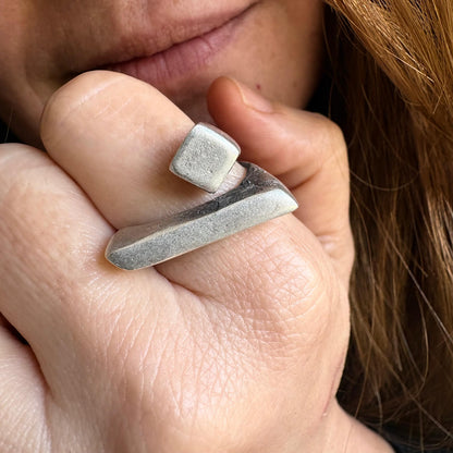 Close-up of a hand wearing two silver rings with a blurred background
