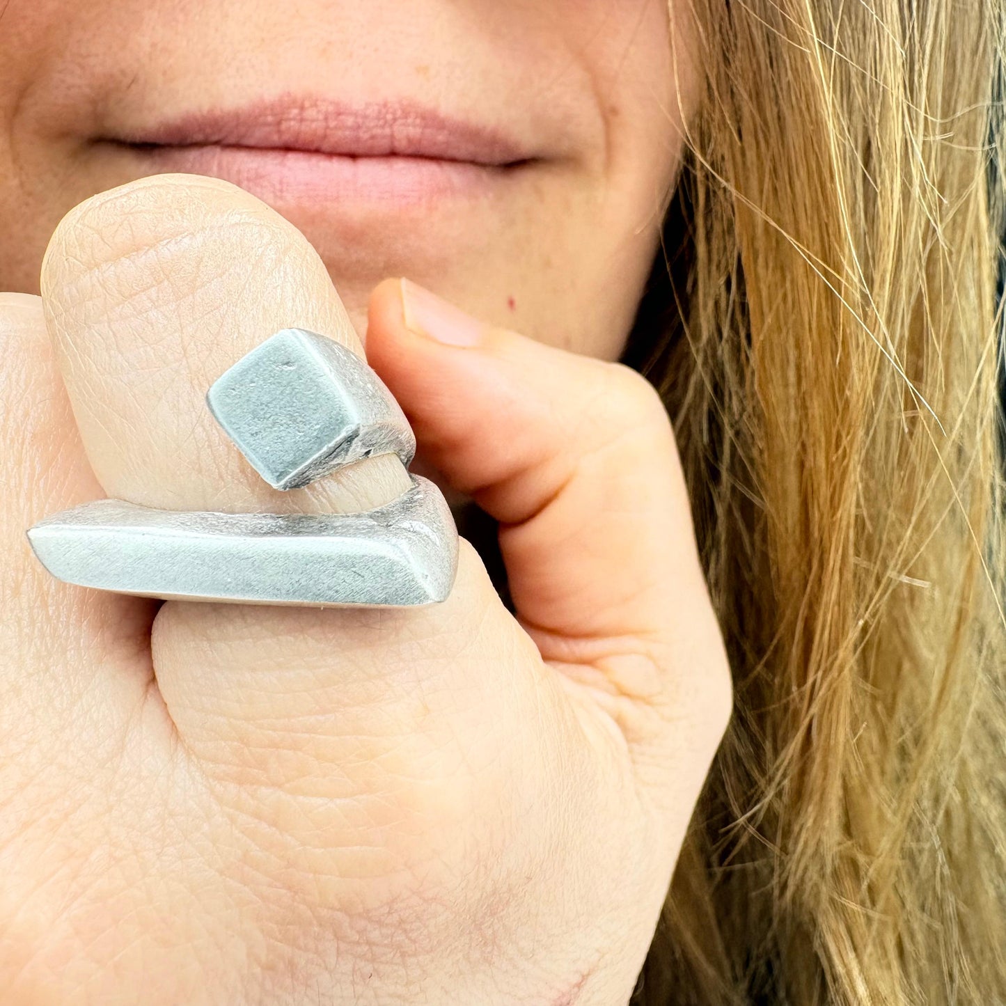 Close-up of a hand wearing two silver rings with a blurred background