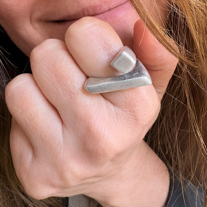Close-up of a hand wearing a silver ring with a geometric design.