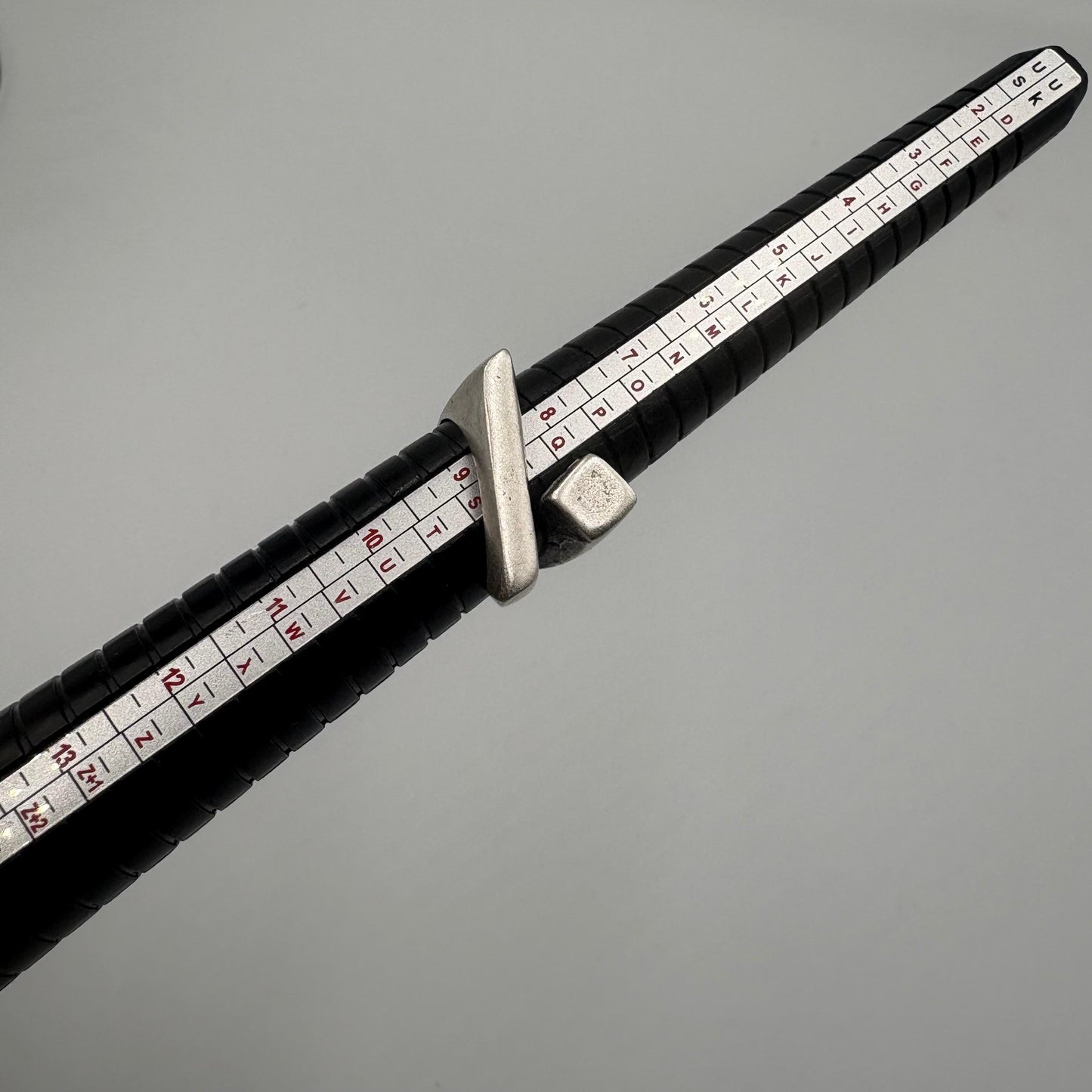 Black measuring tape with white measurement markings on a gray background