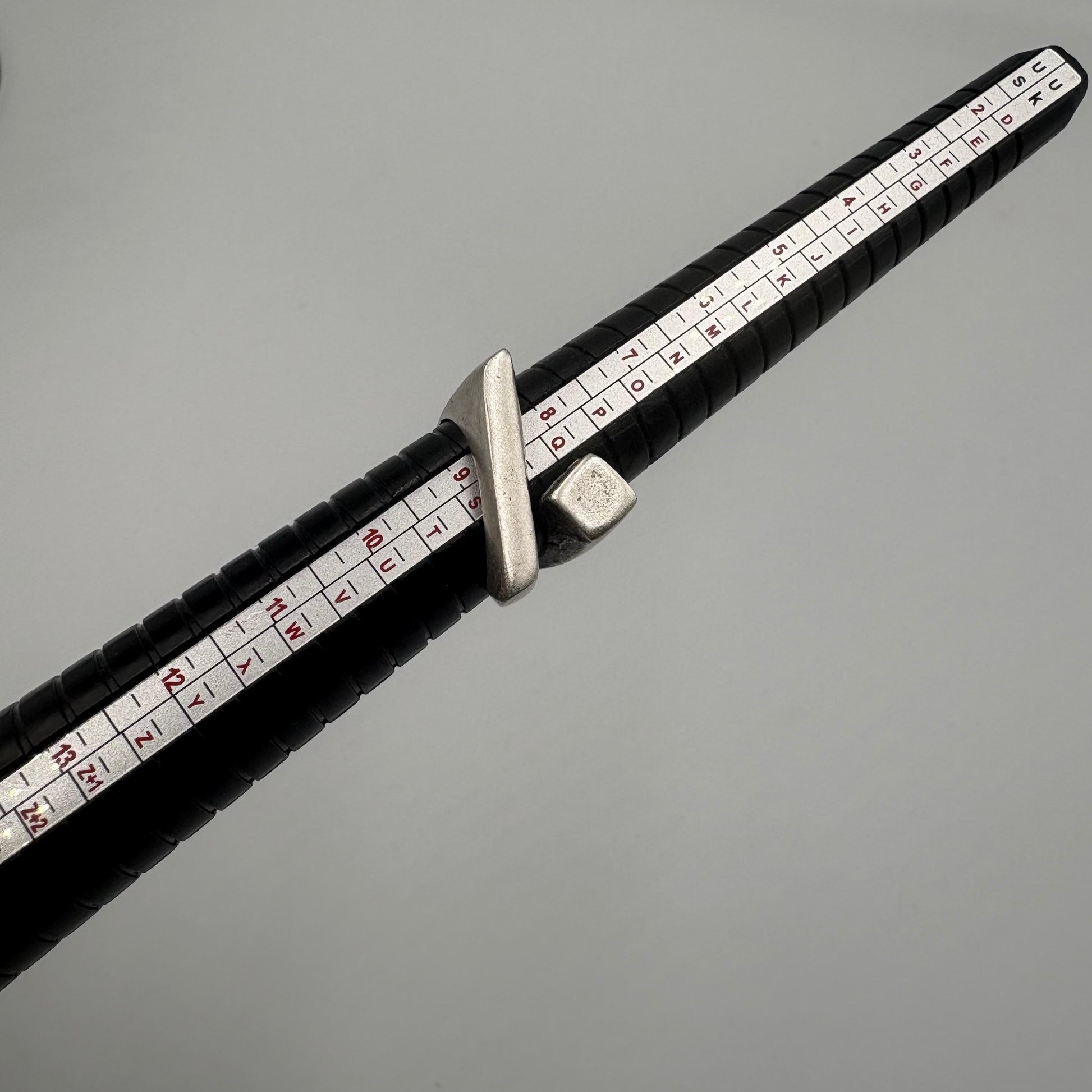 Black measuring tape with white measurement markings on a gray background