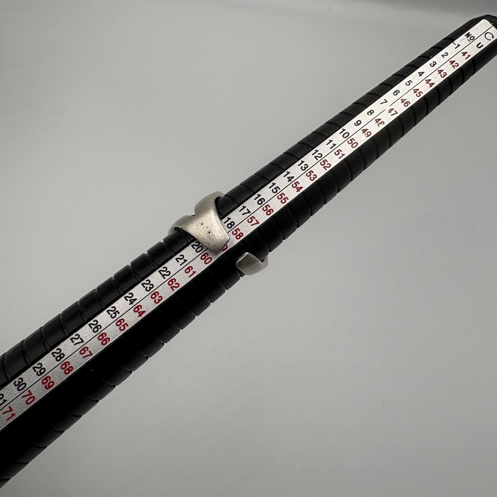 Close-up of a fishing rod with a black handle and red and white measurement scale on a gray background