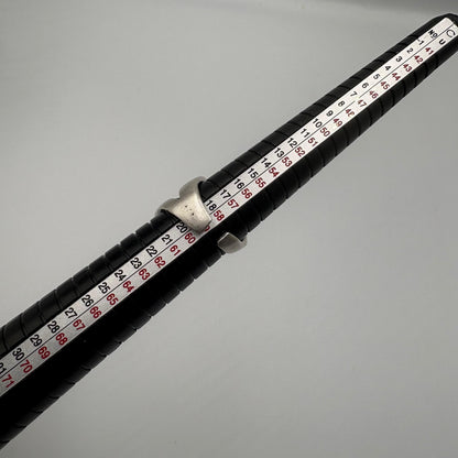Close-up of a fishing rod with a black handle and red and white measurement scale on a gray background