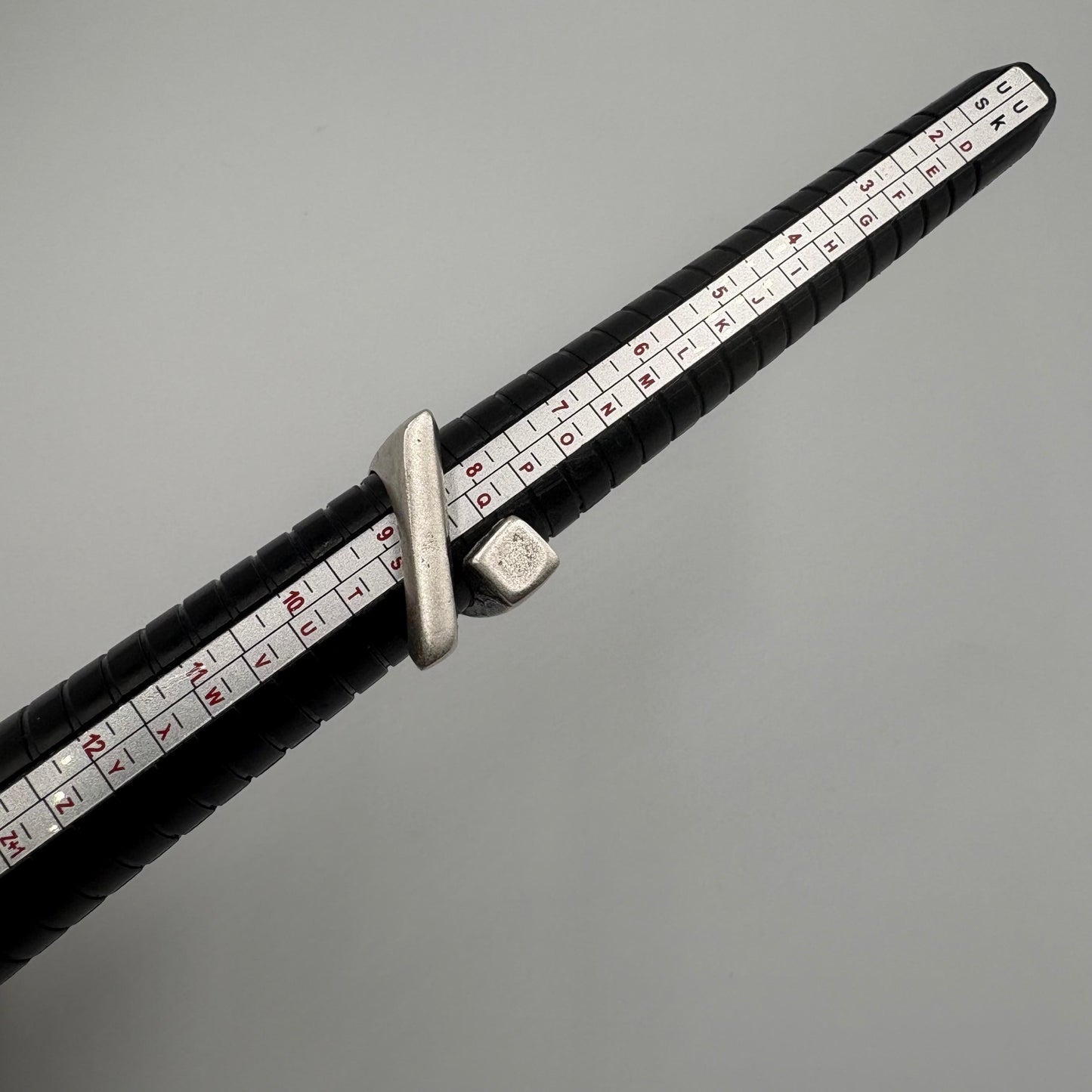 Close-up of a measuring tool with black handle and white measurement scale on a gray background