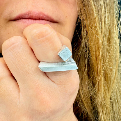 Close-up of a hand wearing a silver ring with a blue stone.